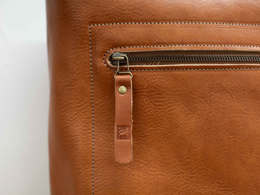 The logo of White Wolf Leather Studio is visible on the zipper pull of the front zipper of the leather bag. 