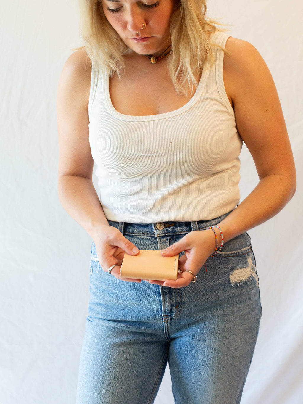 The woman is closing the ethical leather card wallet. 