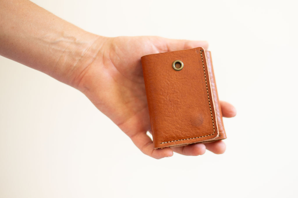 Brown trifold card wallet with cash compartment and eyelet for chain, made with organic leather, sustainably sourced. 