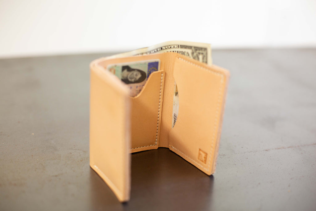 The light tan leather card wallet is shown open to show the compartments and stamped White Wolf Leather Studio logo. 