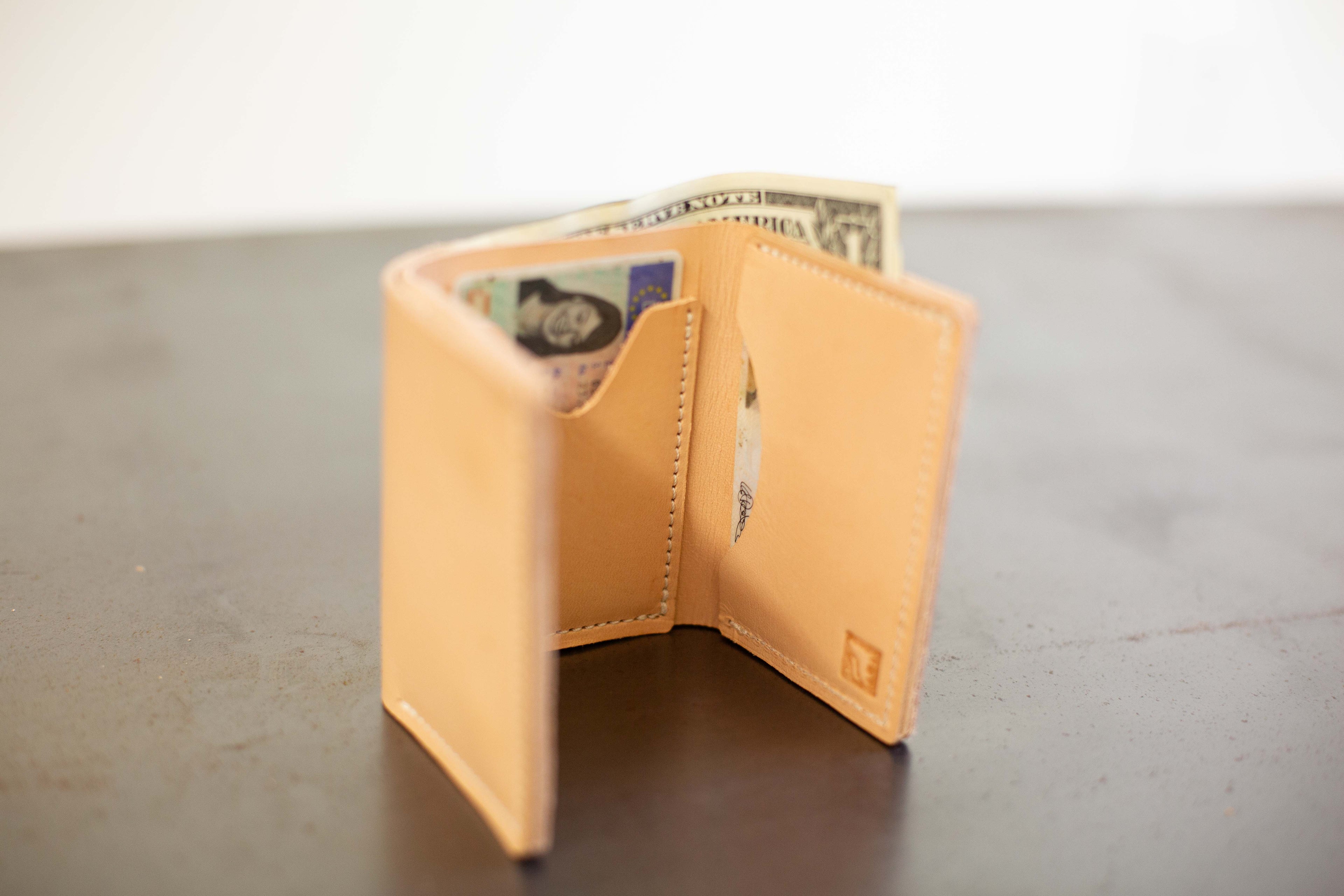 The light tan leather card wallet is shown open to show the compartments and stamped White Wolf Leather Studio logo. 
