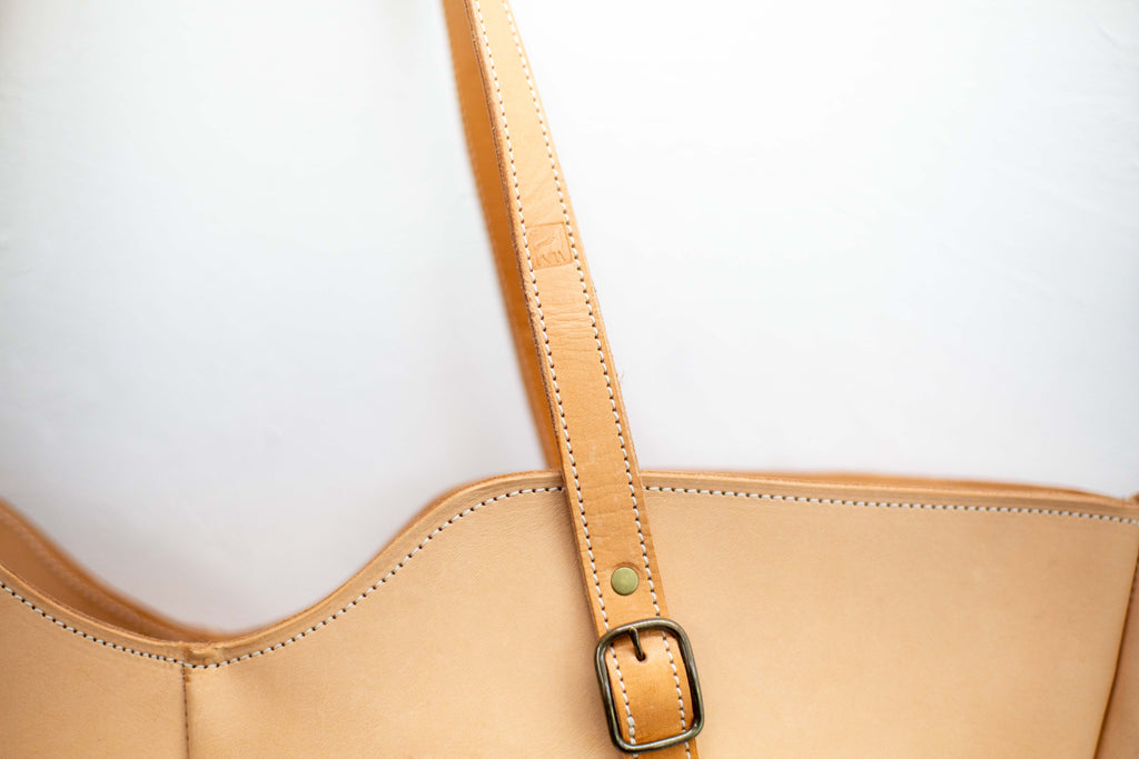 The strap of the sustainable leather bag shows the logo of White Wolf Leather Studio stamped in its strap. 