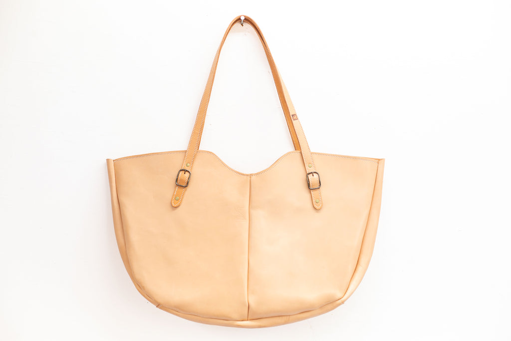 Large shoulder bag in a light, undyed tan color. The leather bag is made to be durable and with fair leather, made from hides from cattle from organic and regenerative farms. 