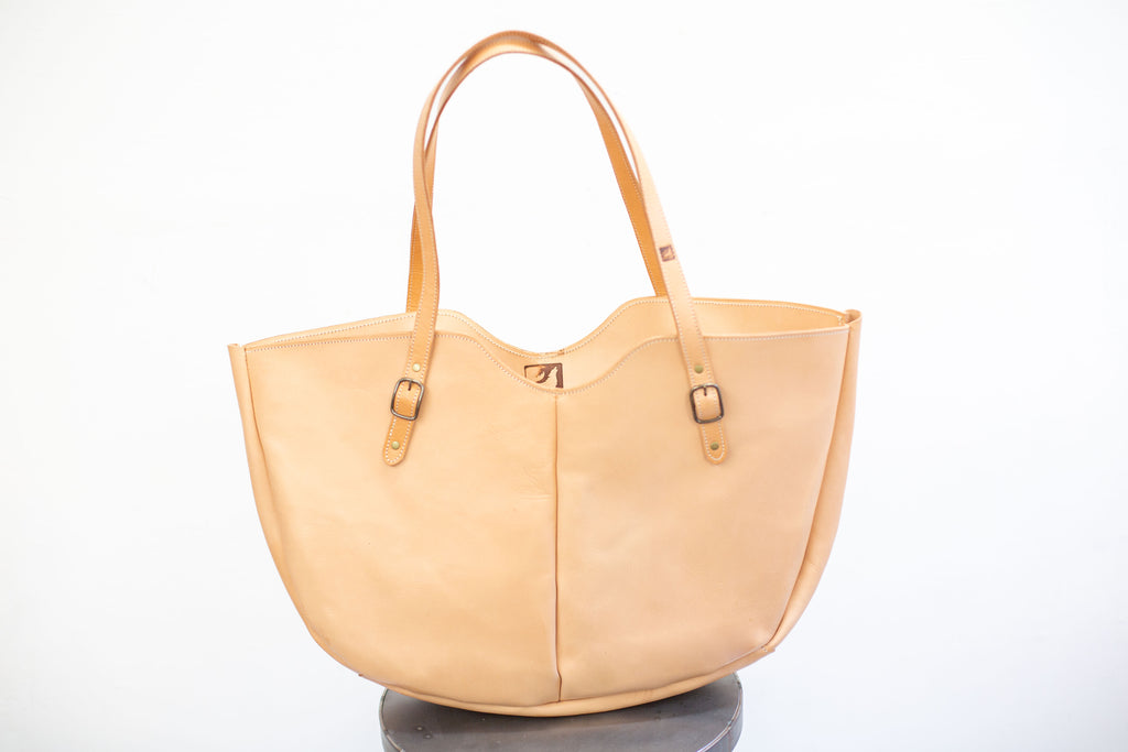 The large leather shoulder bag is inspired in its design by the seventies and made with sustainable leather. 