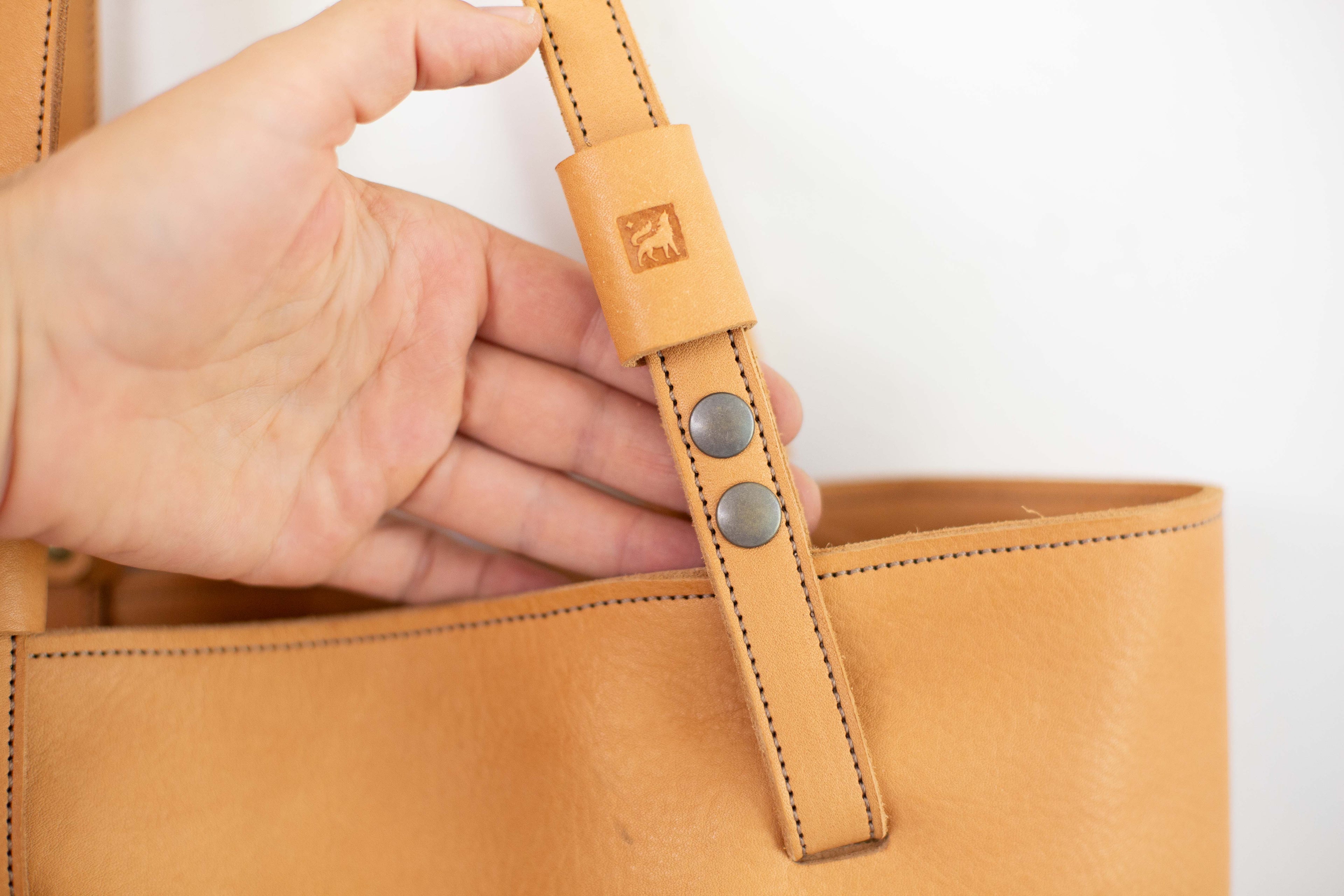 Close up to show the snaps of the removable handles of the leather bag. 