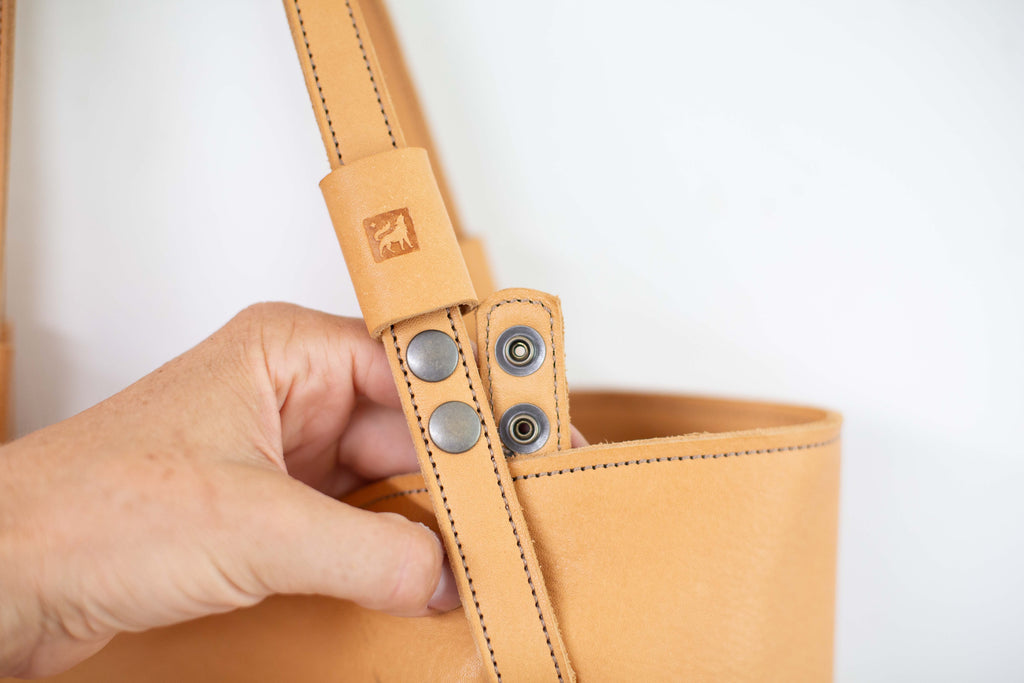 Close up to show the snaps of the removable handles of the leather bag. 