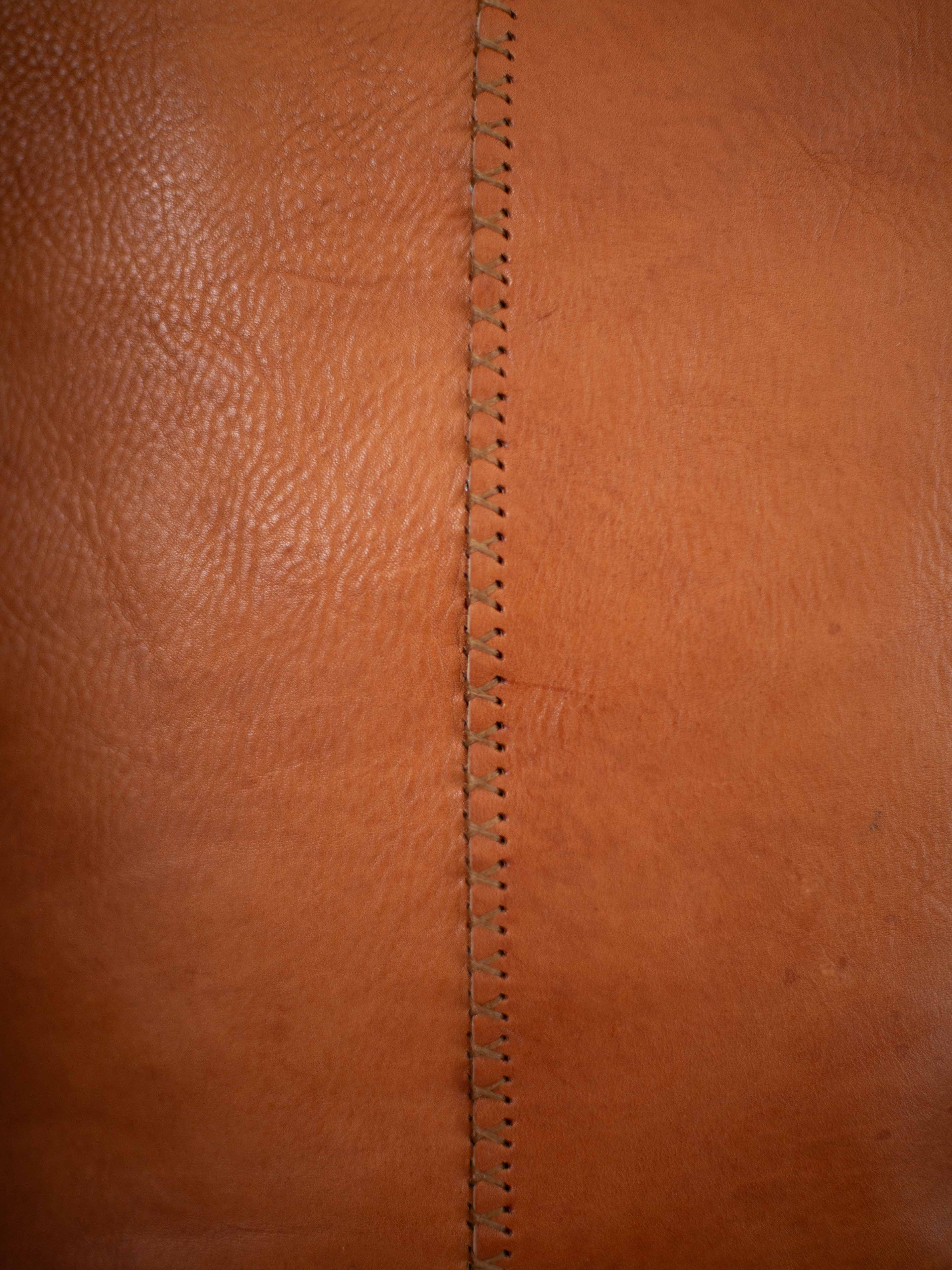 A close-up on the hand stitched seam on the back of the leather tote and the sustainable leather. 