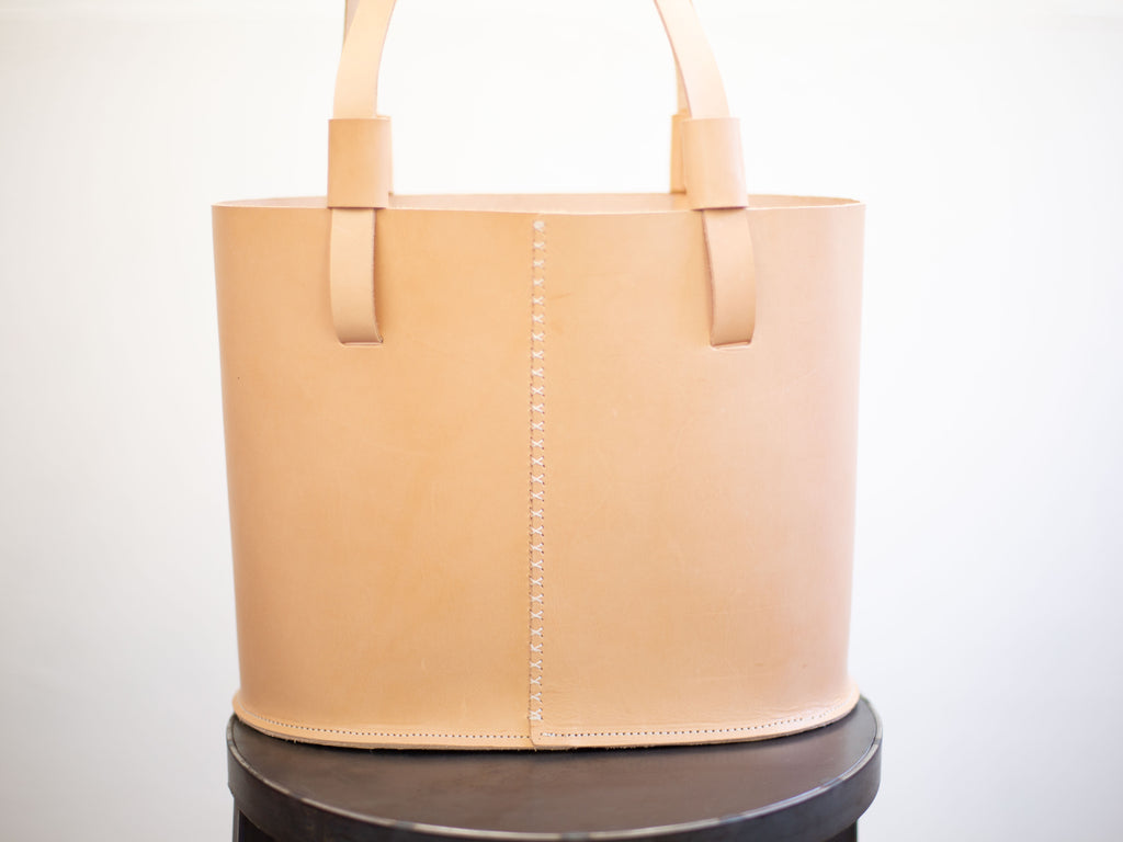The backside of the veg tan leather tote shows the hand stitched seam on the back of the shoulder bag. 