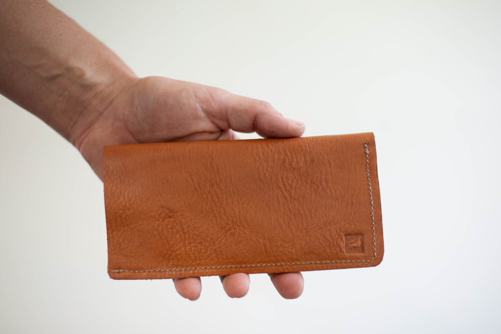 The backside of the handmade sustainable leather wallet shows the logo of White Wolf Leather Studio, a woman owned small business. 