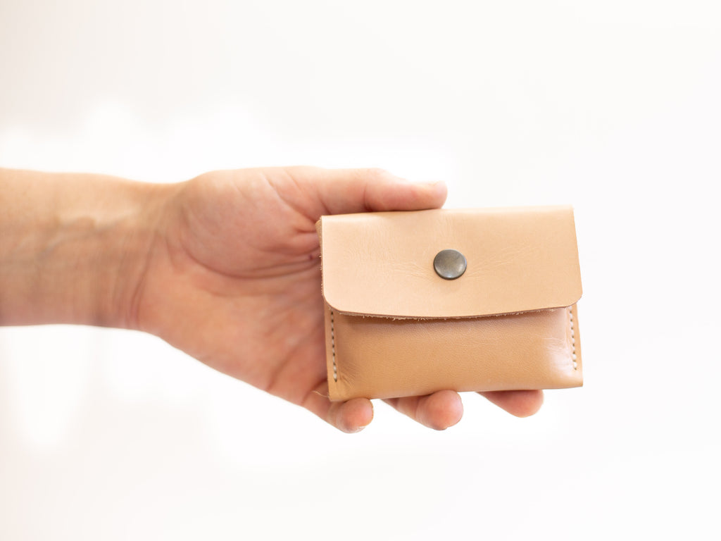 Small leather wallet for coins, closed with snap button and made with organic regenerative veg tanned leather.