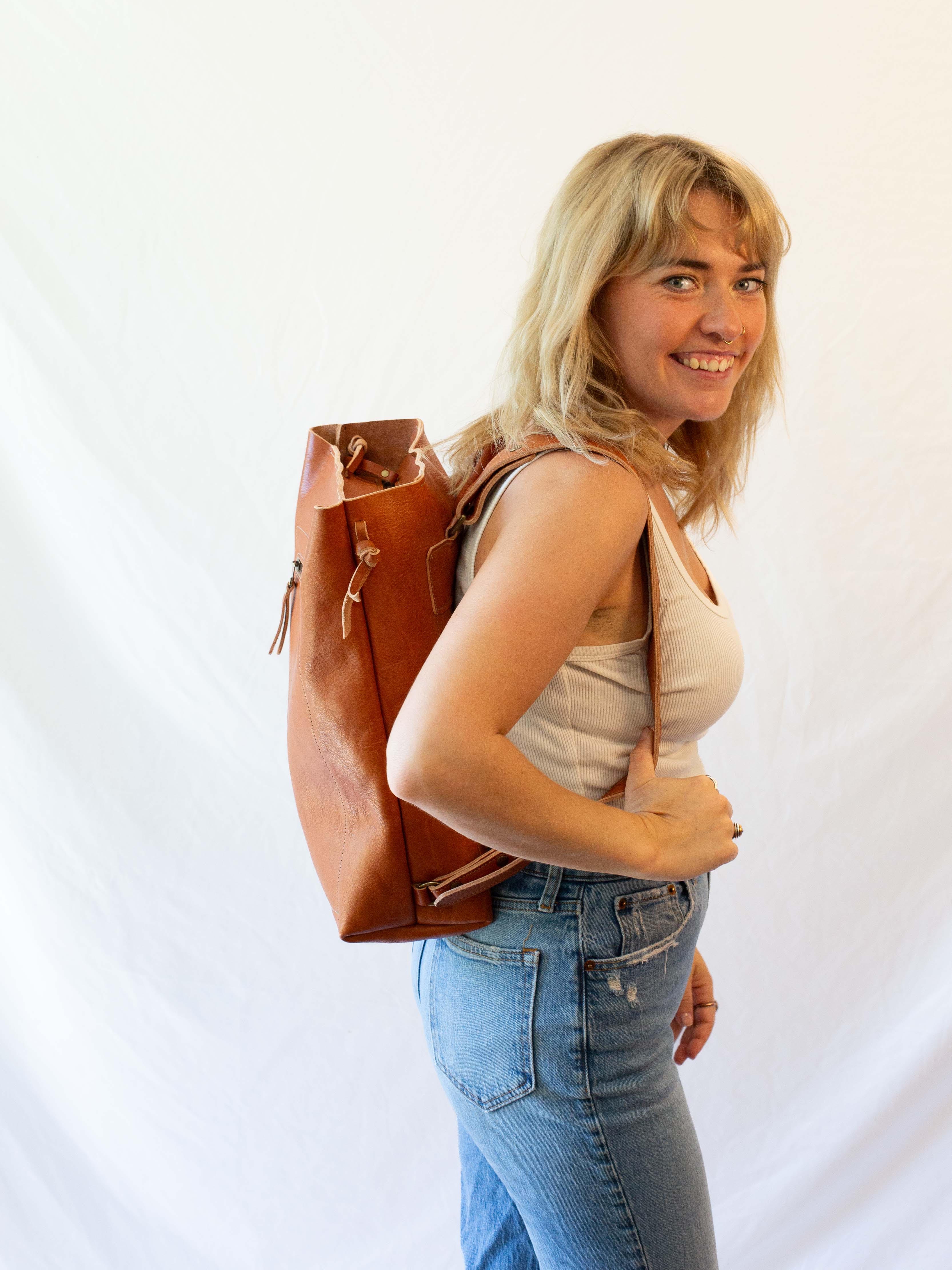 Side view of the sustainable leather backpack that is being worn by a model. 