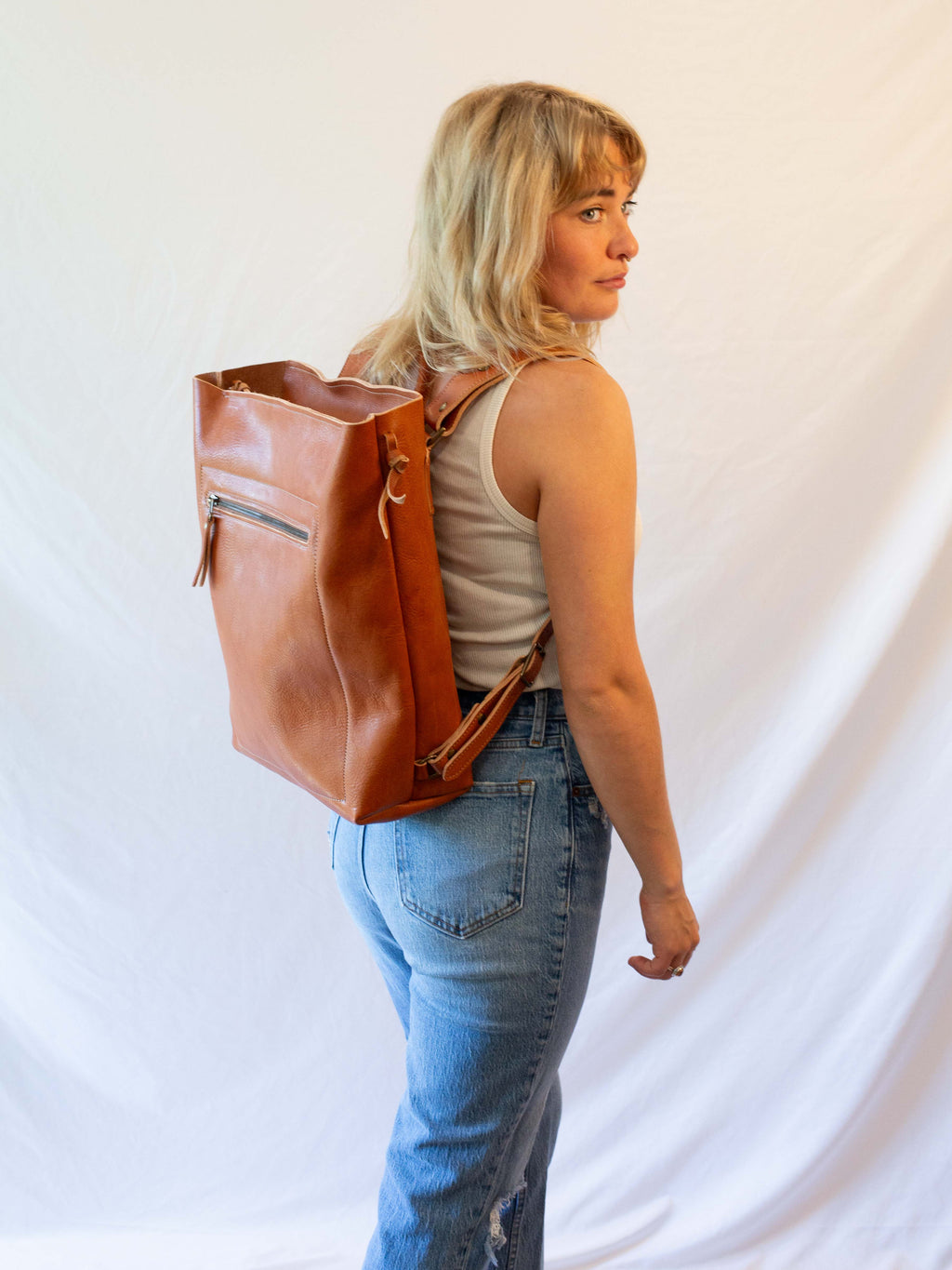 The leather backpack is made from sustainably sourced, reddish brown leather. 