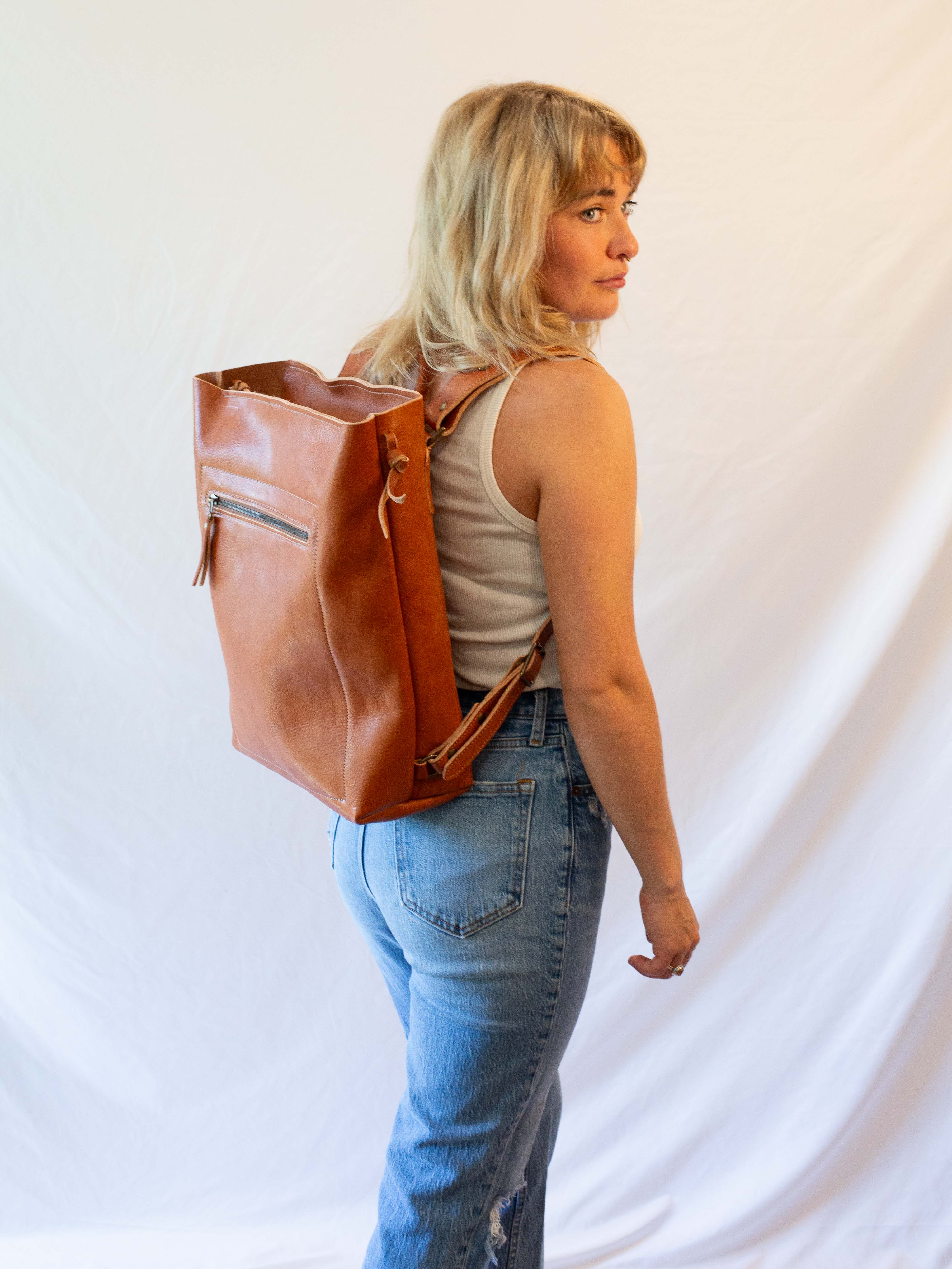 The leather backpack is made from sustainably sourced, reddish brown leather. 