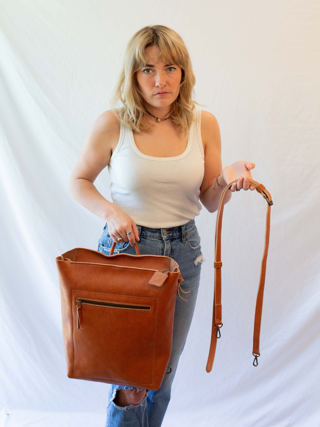 The leather backpack can be converted to a messenger bag  by attaching a crossbody strap. 