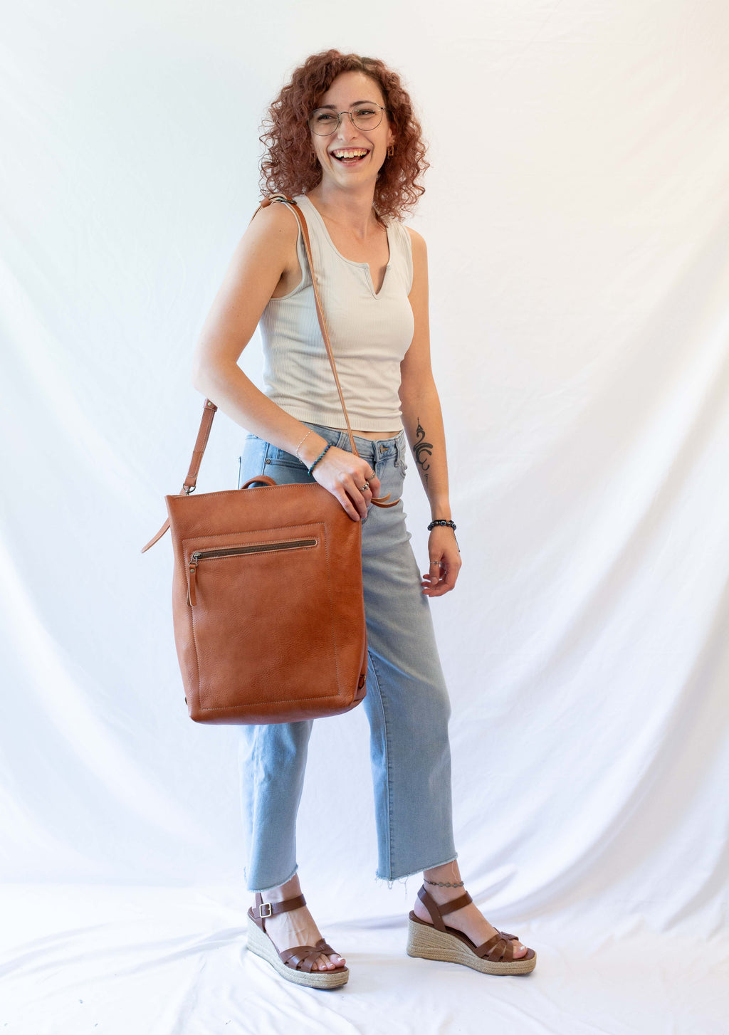 The leather bag is worn by a model to show how it looks in proportion to a person. 