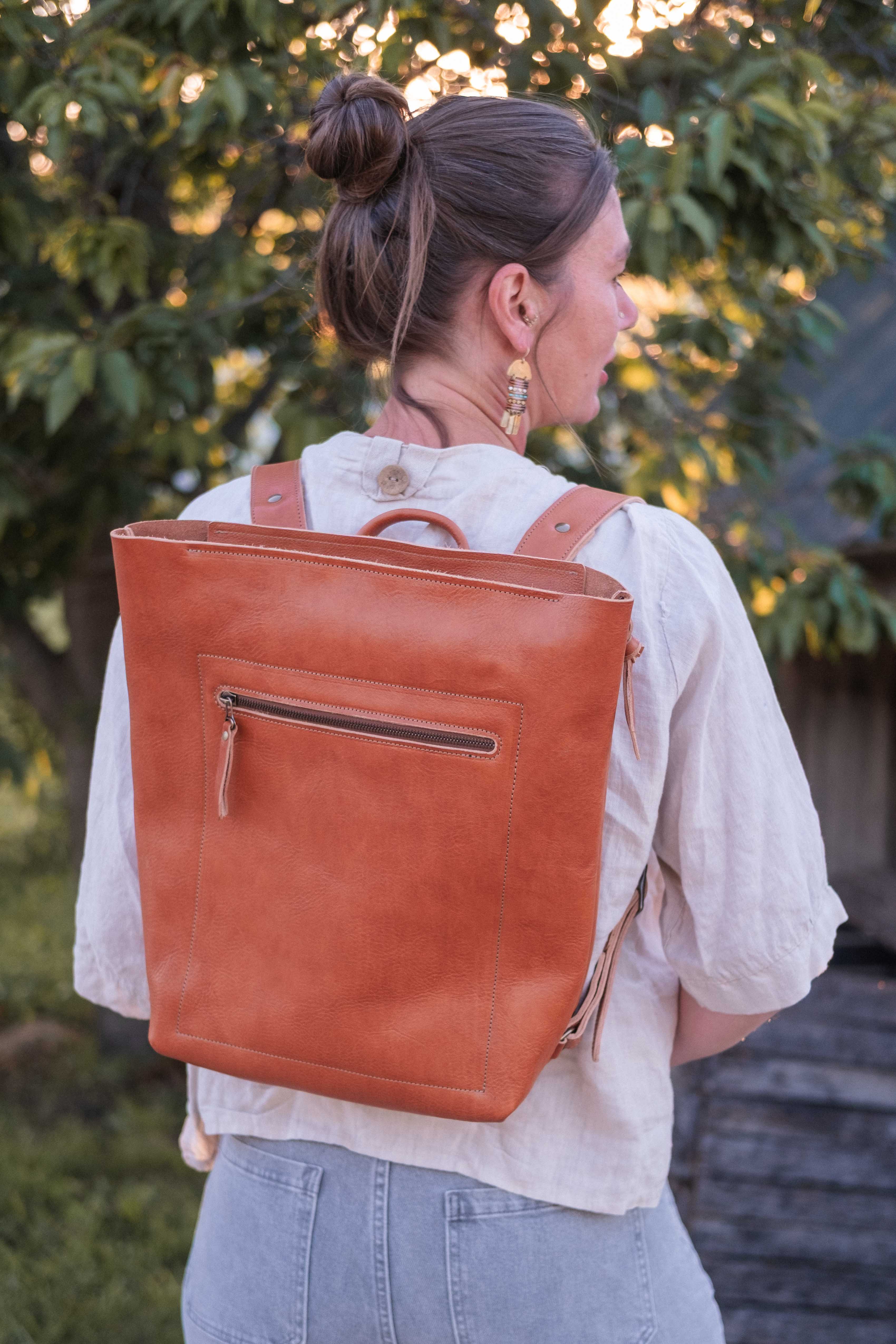 The leather backpack has a front compartment that is closed with a zipper, and a main compartment with interior pocket that is also closed with a zipper. 