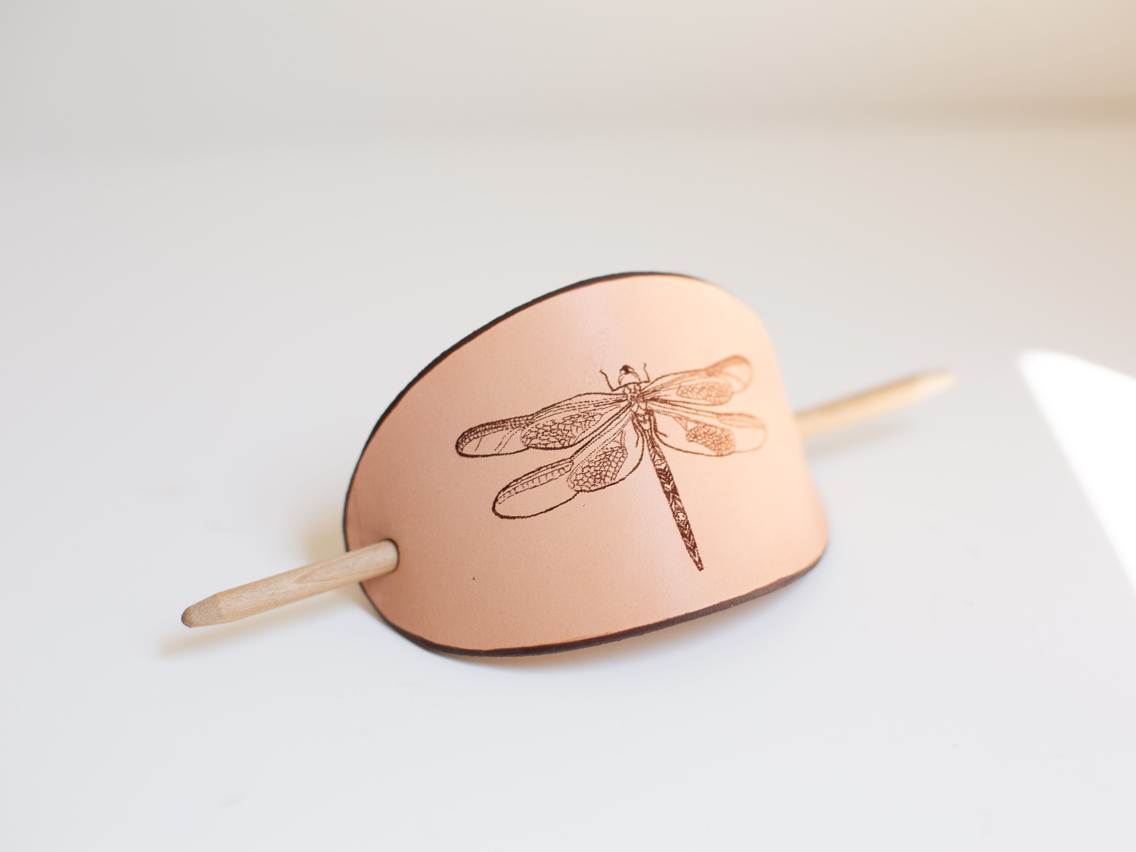 Seen from a slight side angle the picture shows the exact color of the organic leather barrette with the artistic rendering of a dragonfly. 