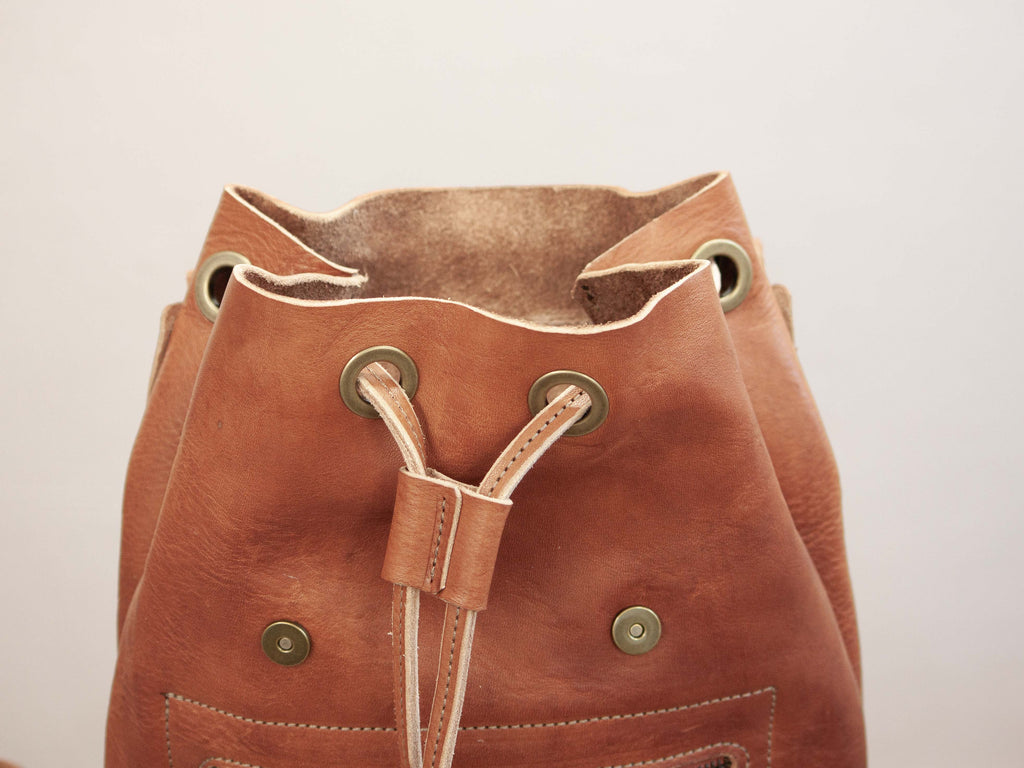A close-up view of the drawstring closure of the small handmade leather backpack. 