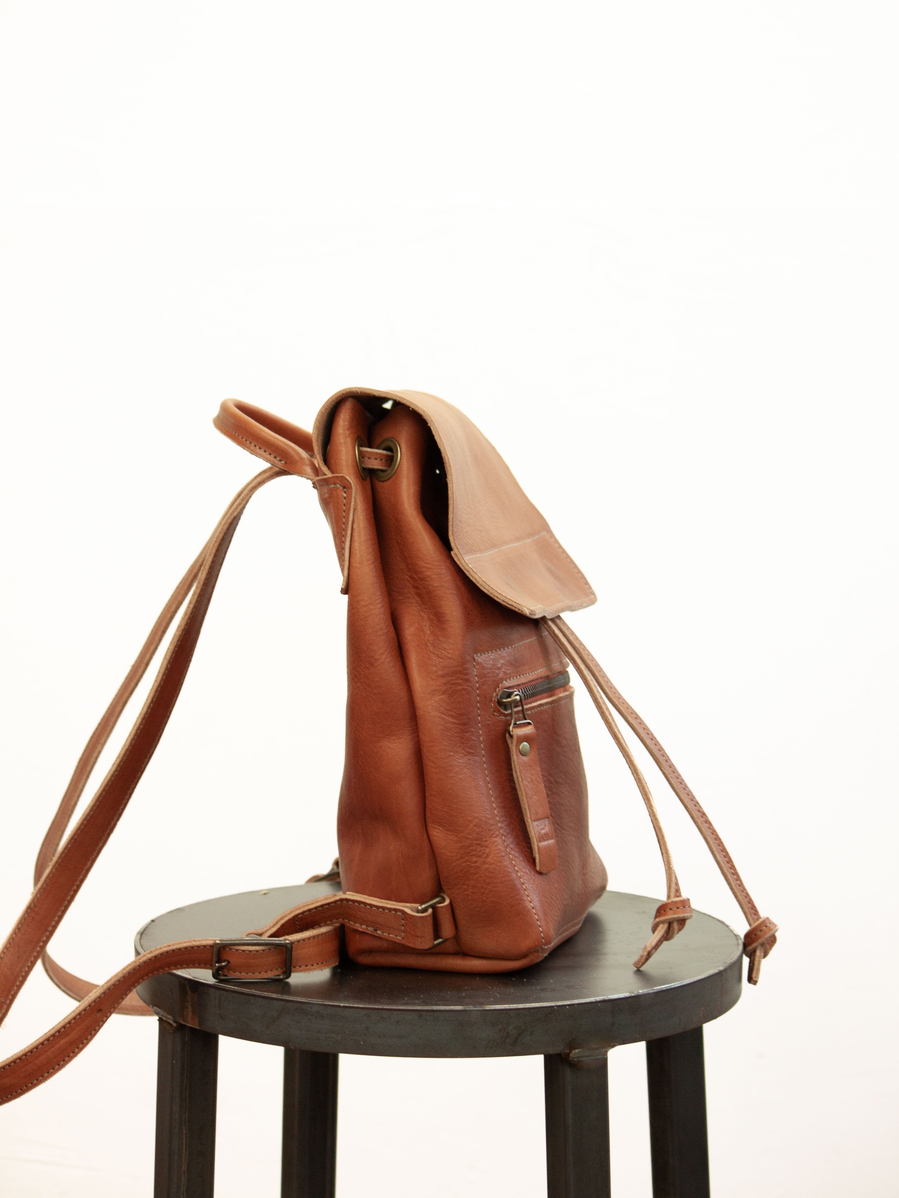 The small drawstring backpack with sustainable leather is seen from the side. 
