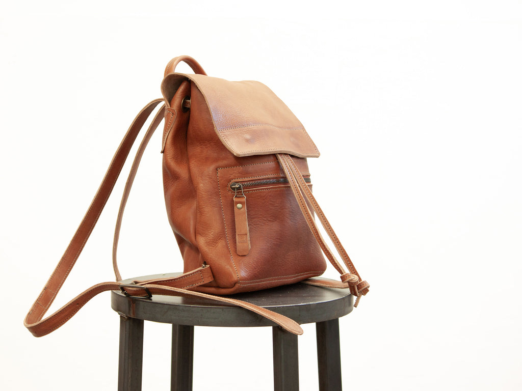 The small leather drawstring backpack is seen from the side. The side-view shows details in the make. 