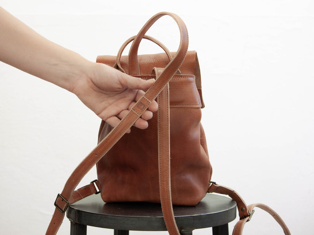 The White Wolf Leather Studio logo on the backpack strap is highlighted by someone holding it into the camera. 