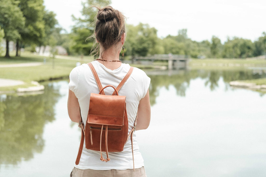The woman owner of White Wolf Leather Studio is wearing the small brown leather drawstring backpack to show how it looks when in use. 
