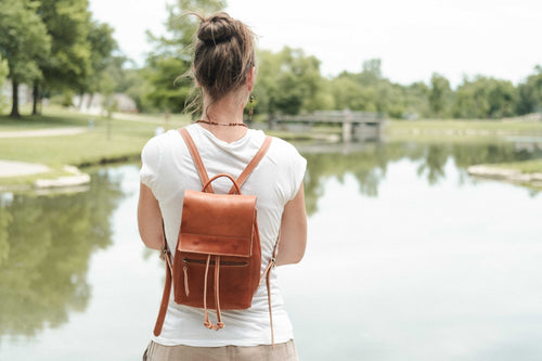 The woman owner of White Wolf Leather Studio is wearing the small brown leather drawstring backpack to show how it looks when in use. 