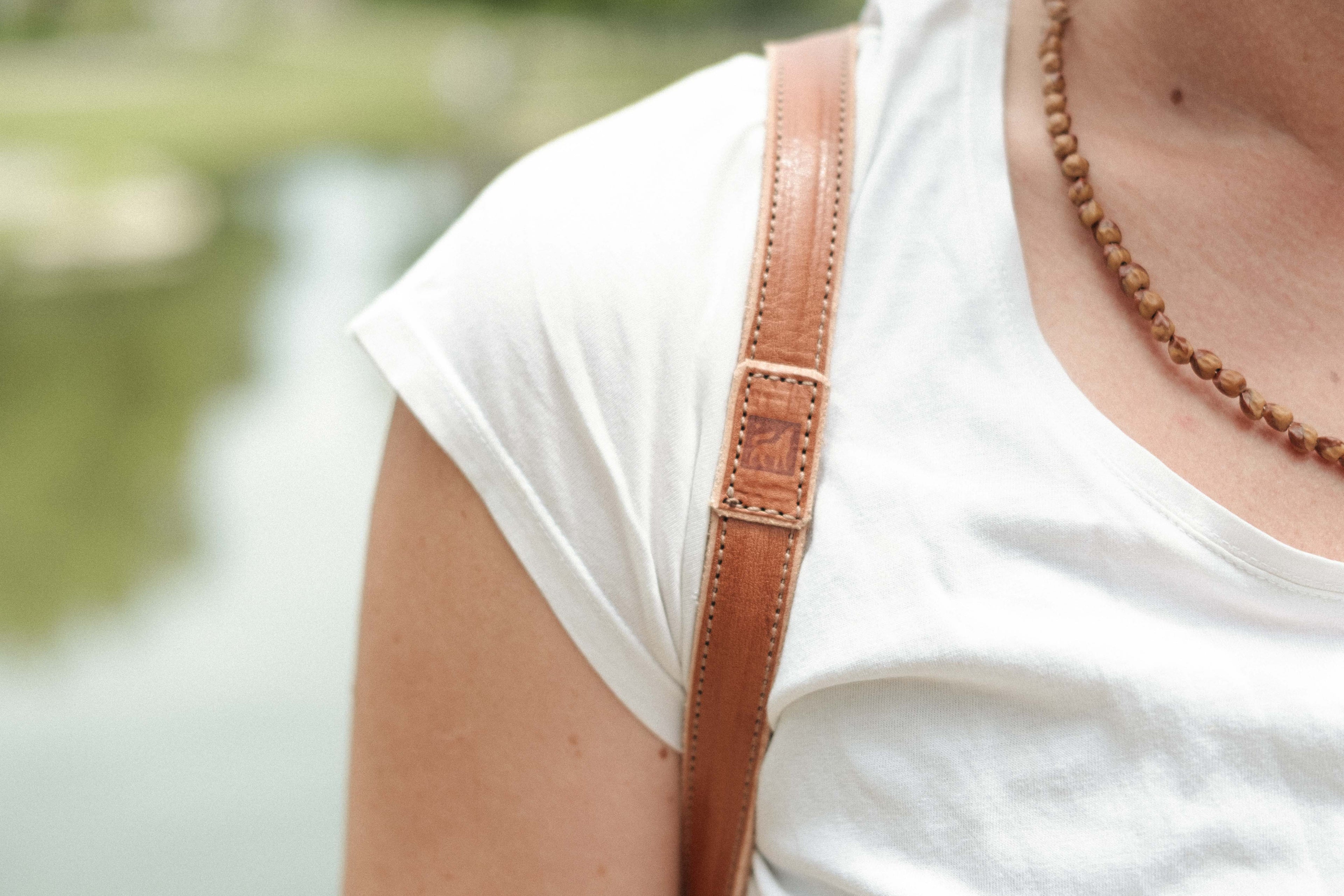 The thin 3/4" backpack straps of the leather drawstring backpack show the burned logo of White Wolf Leather Studio. 