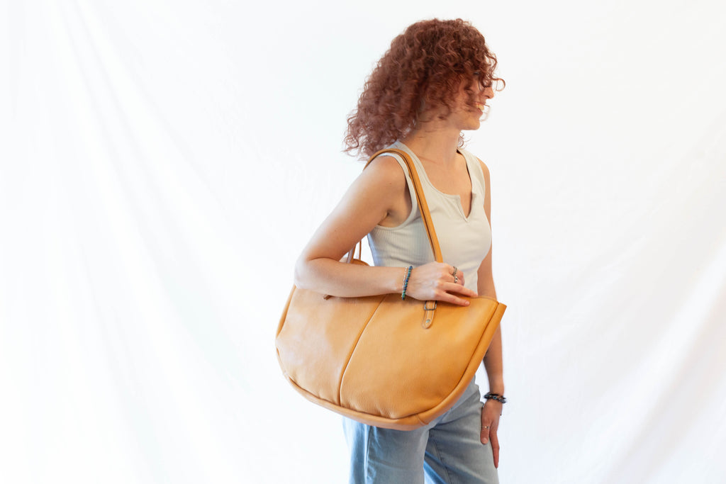 A leather hobo bag is held by a model to show the overall size and look of the bag. 