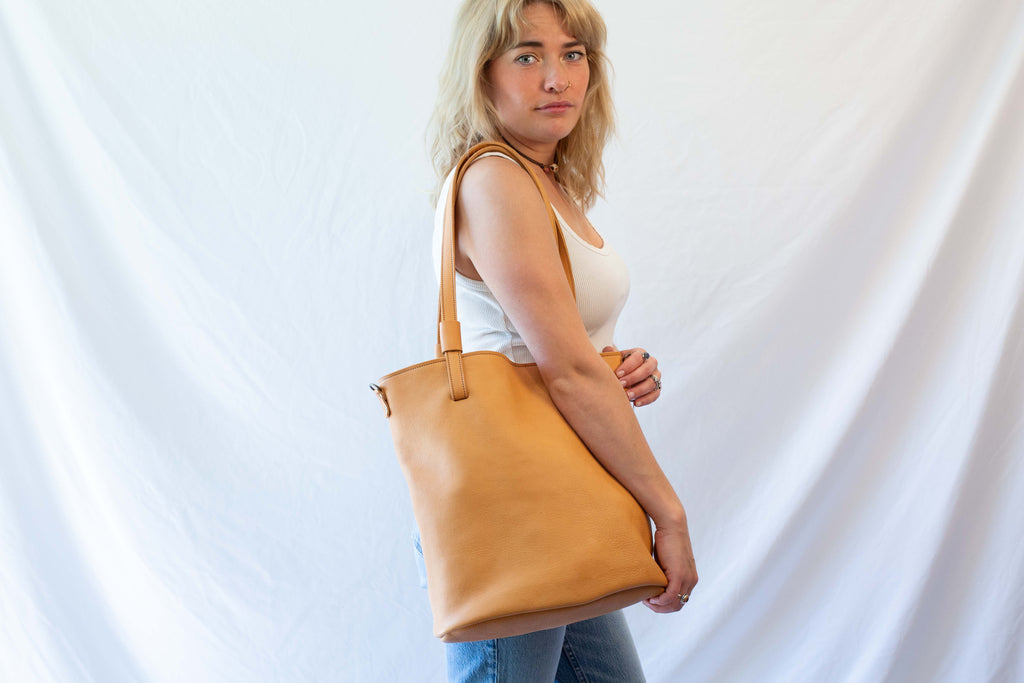 Large leather tote bag worn over the shoulder. Dark beige sustainable leather. 