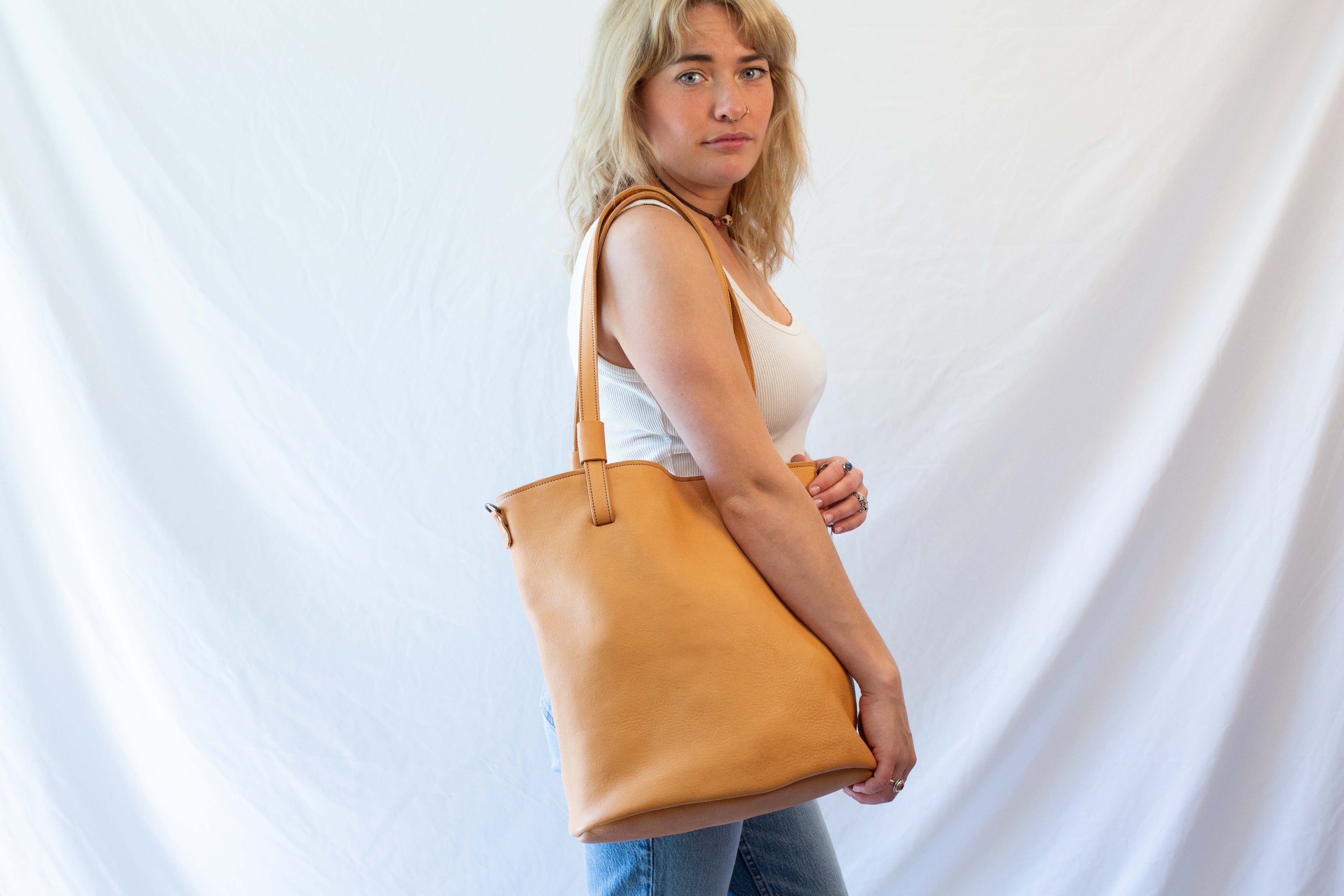 Large leather tote bag worn over the shoulder. Dark beige sustainable leather. 