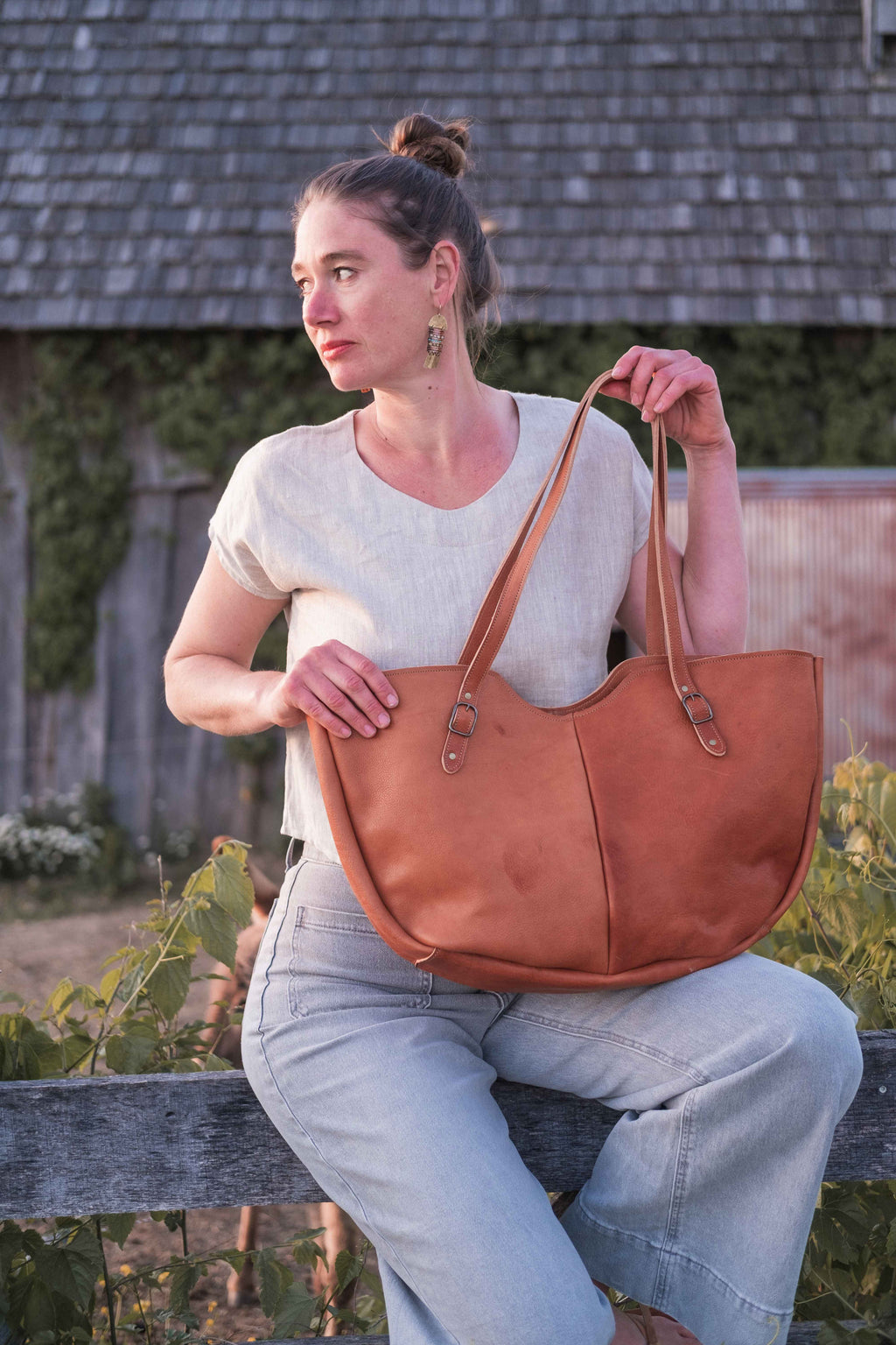 The owner of the business is modeling the large leather tote bag, model "The Wanderer", in the light chestnut brown leather. 