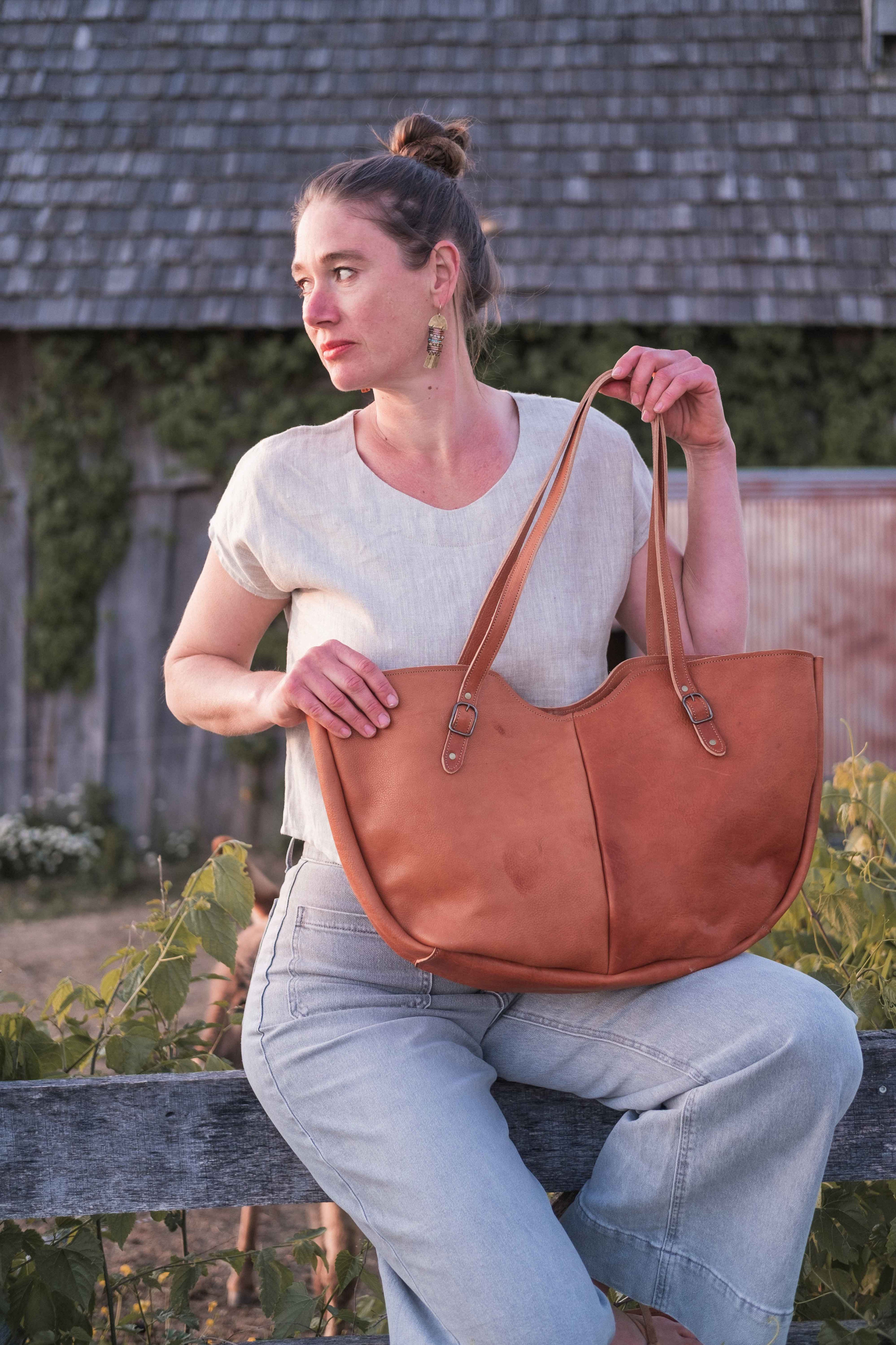 The owner of the business is modeling the large leather tote bag, model "The Wanderer", in the light chestnut brown leather. 