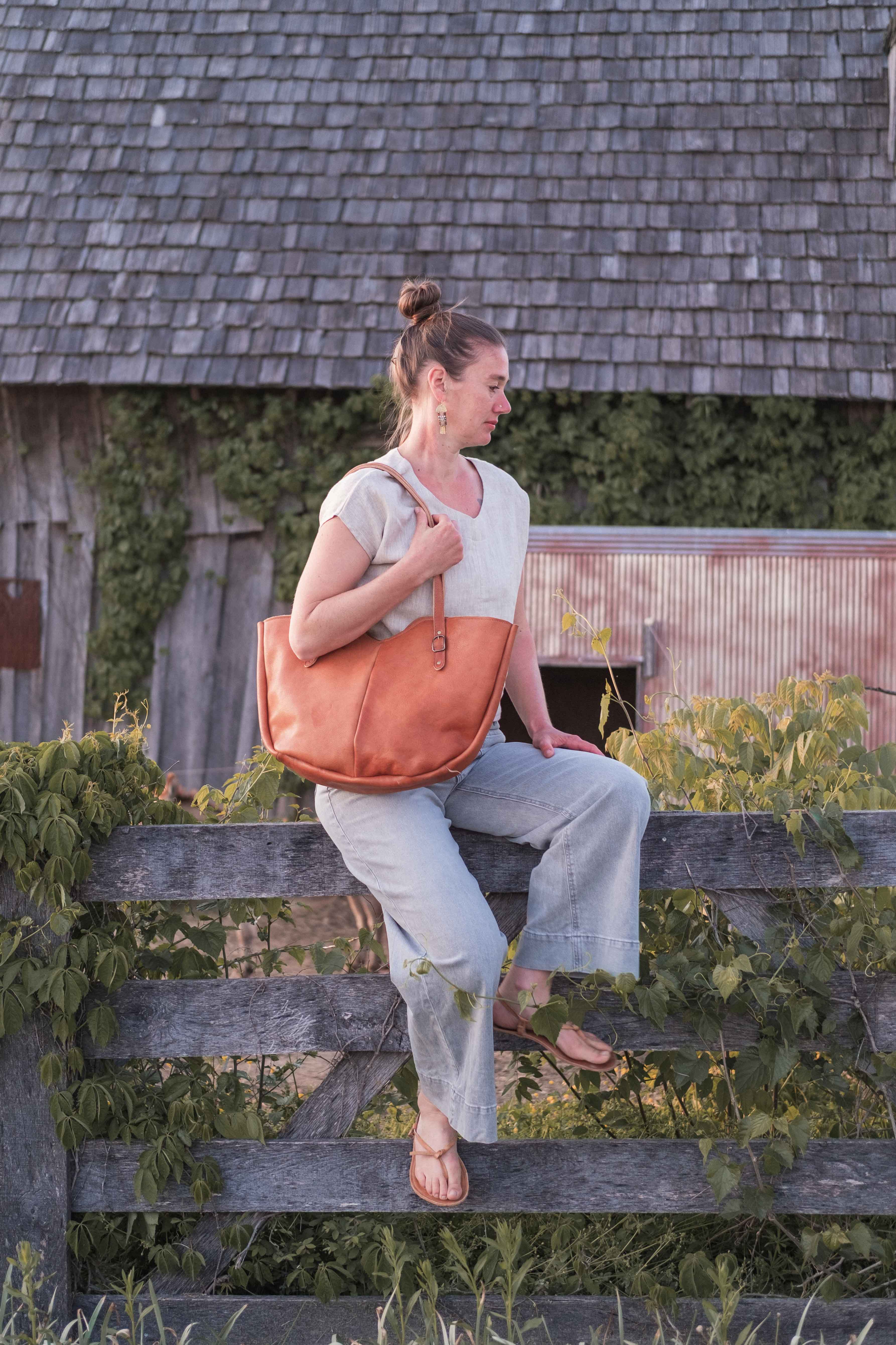 The large leather shoulder bag, model "The Wanderer" is being worn by a model to show how it looks in real life. 