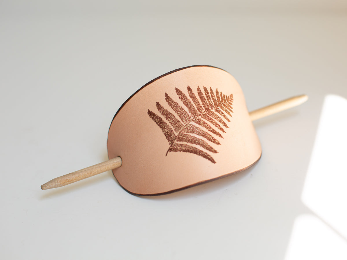 The fern is the digitalization of a hand drawn fine art drawing, laser engraved into the veg tan leather for this large hair stick barrette. 