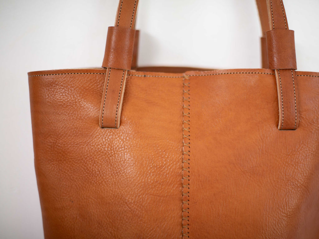 The seam on the back of the sustainable leather tote is sewn by hand with a cross stitch. 