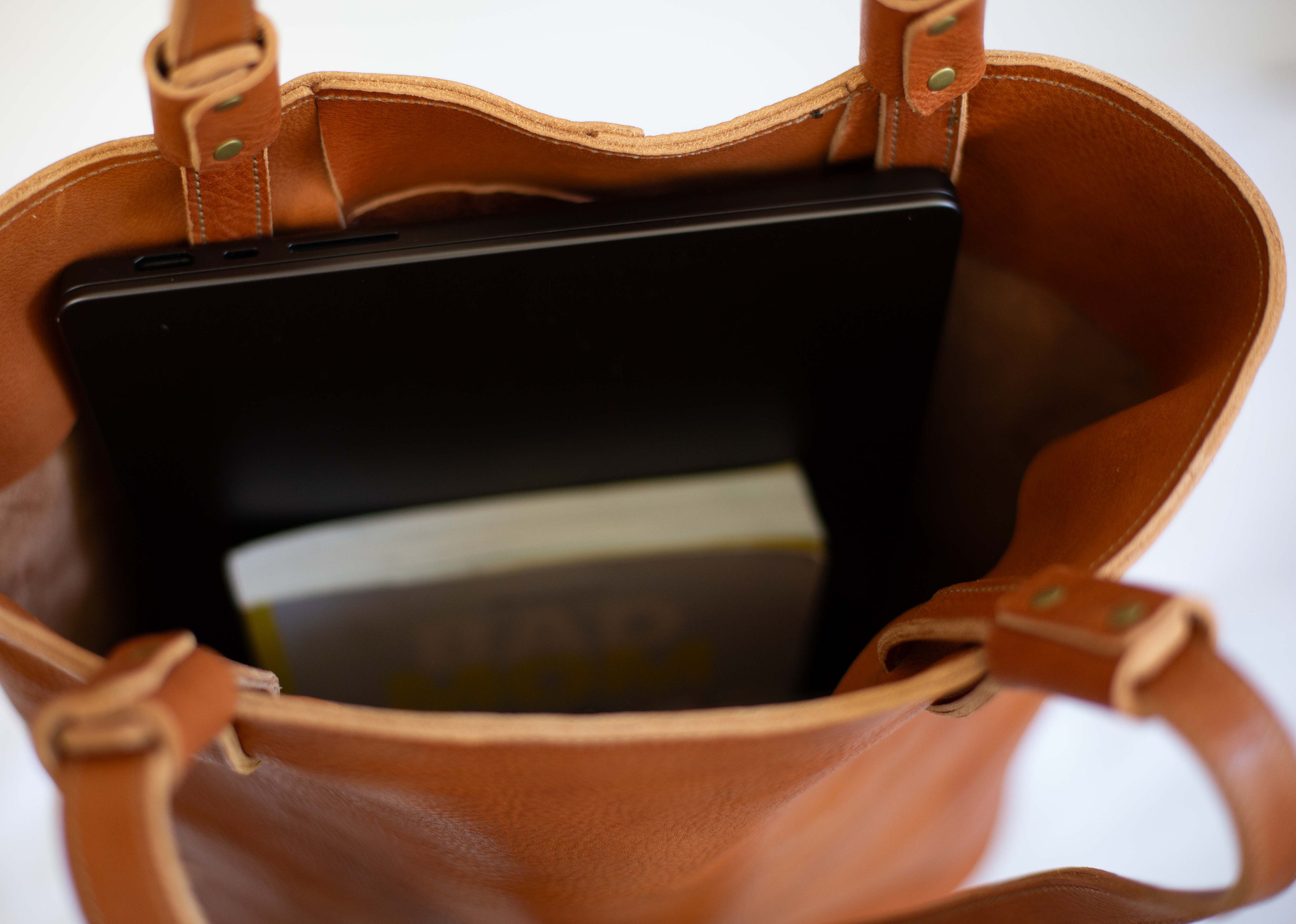 The leather tote with organic sustainable leather is large to fit a notebook and several books in it. It also features an inside phone pocket. 
