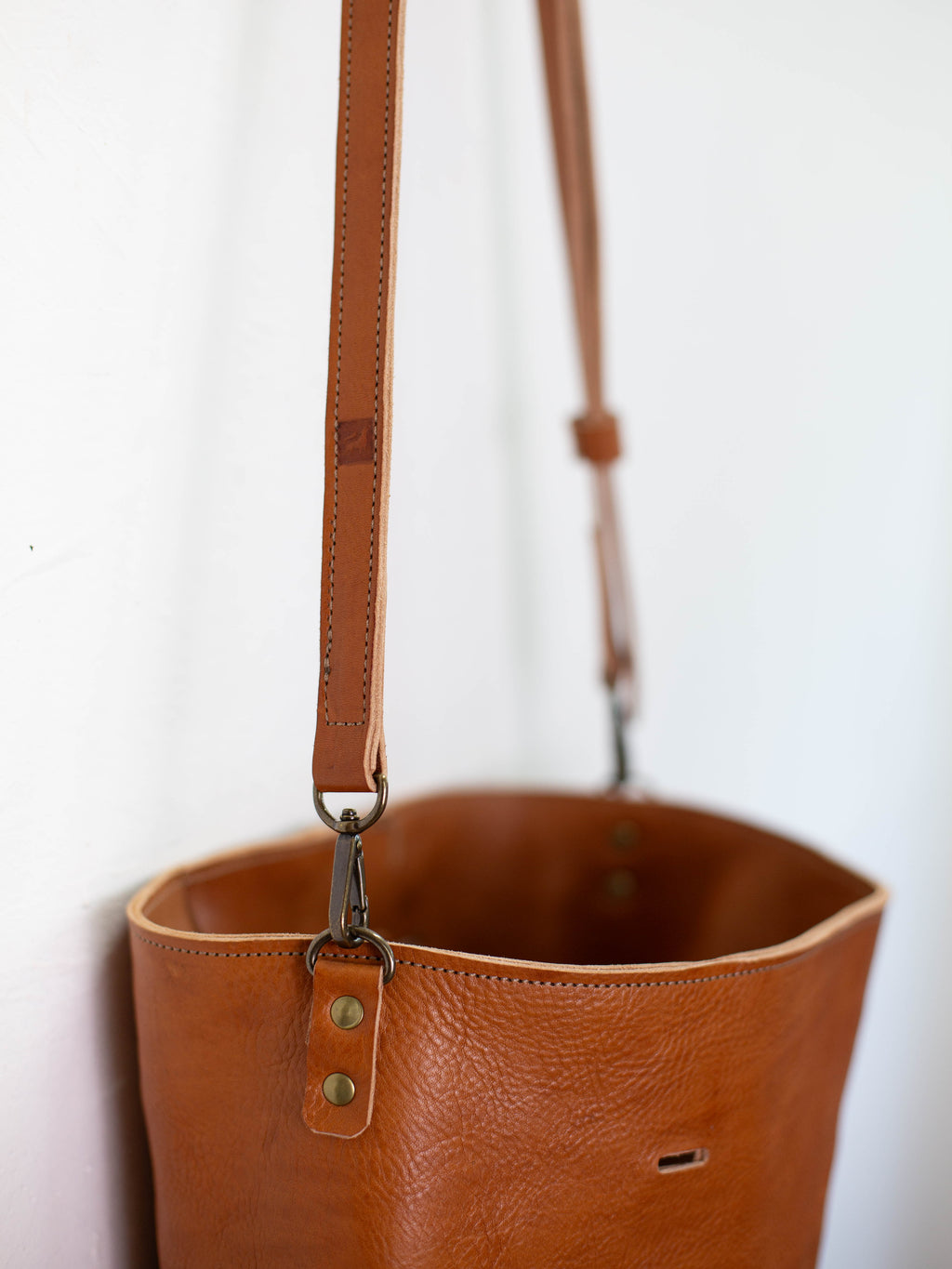 The optional and detachable crossbody strap is stamped with the White Wolf Leather Studio logo. 