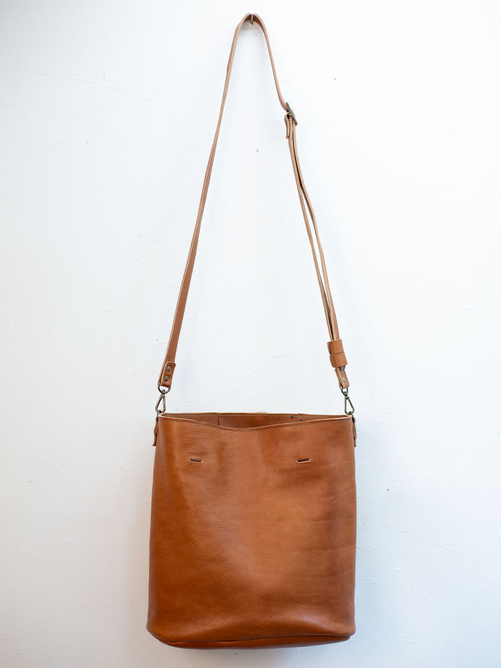 The large sustainable leather tote can be turned into a crossbody bag by attaching the crossbody strap and taking the handles off. 