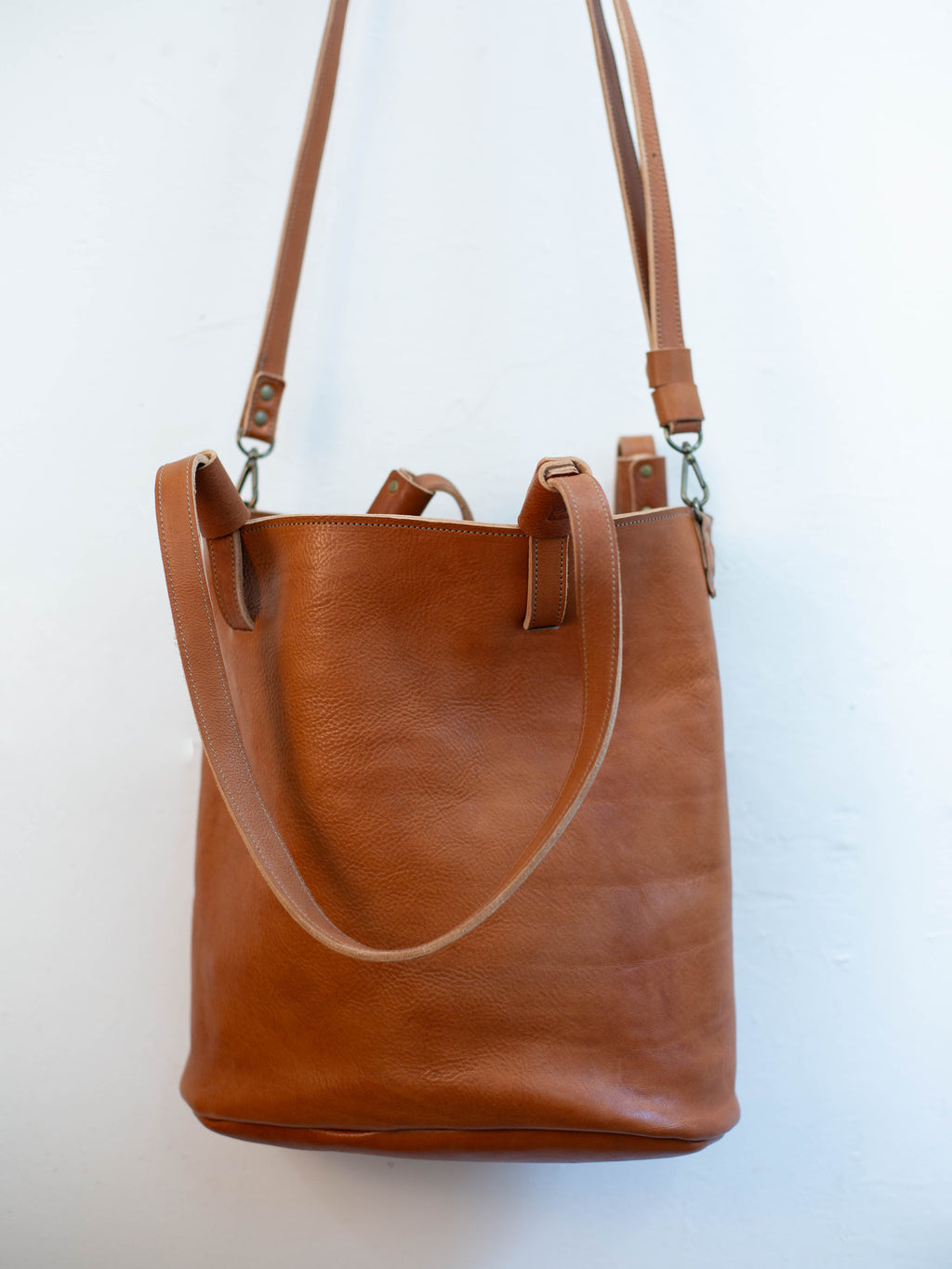 The sustainable leather shoulder bag can be used with an optional crossbody bag. 