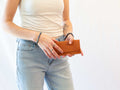 A model is holding the leather cash cover wallet with card slot to show the size proportions. 