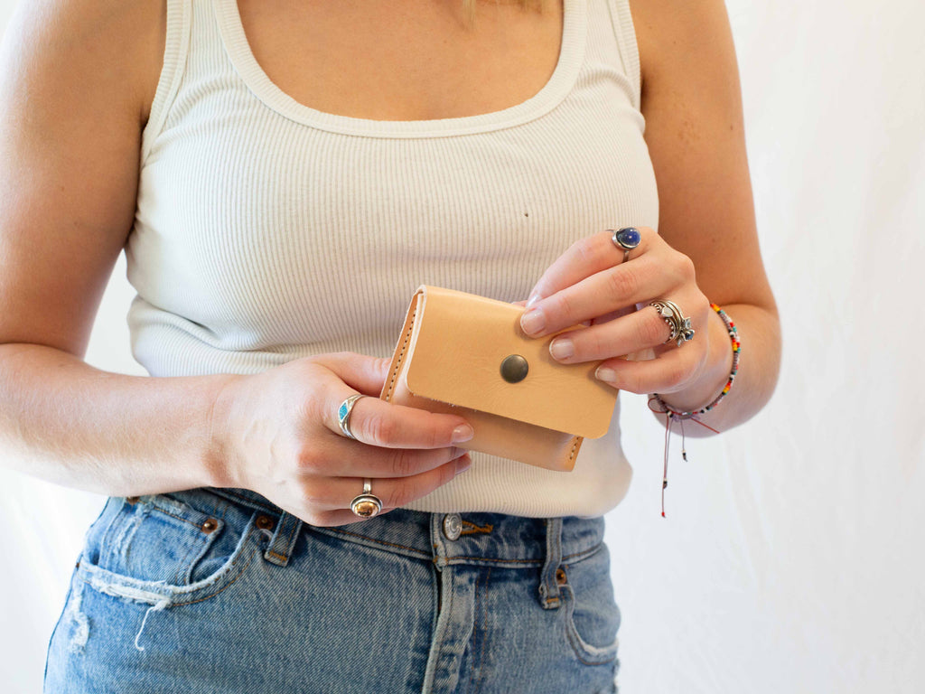 The model is holding the small leather wallet to show its size in relation to a person. 