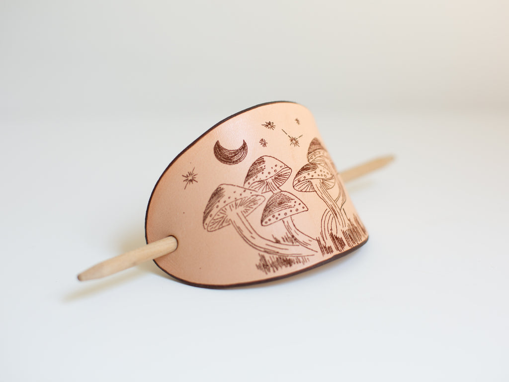 The large barrette is made with non-toxic, sustainably sourced leather and has a laser engraved mushroom design that is the digitalization of an original art drawing. 