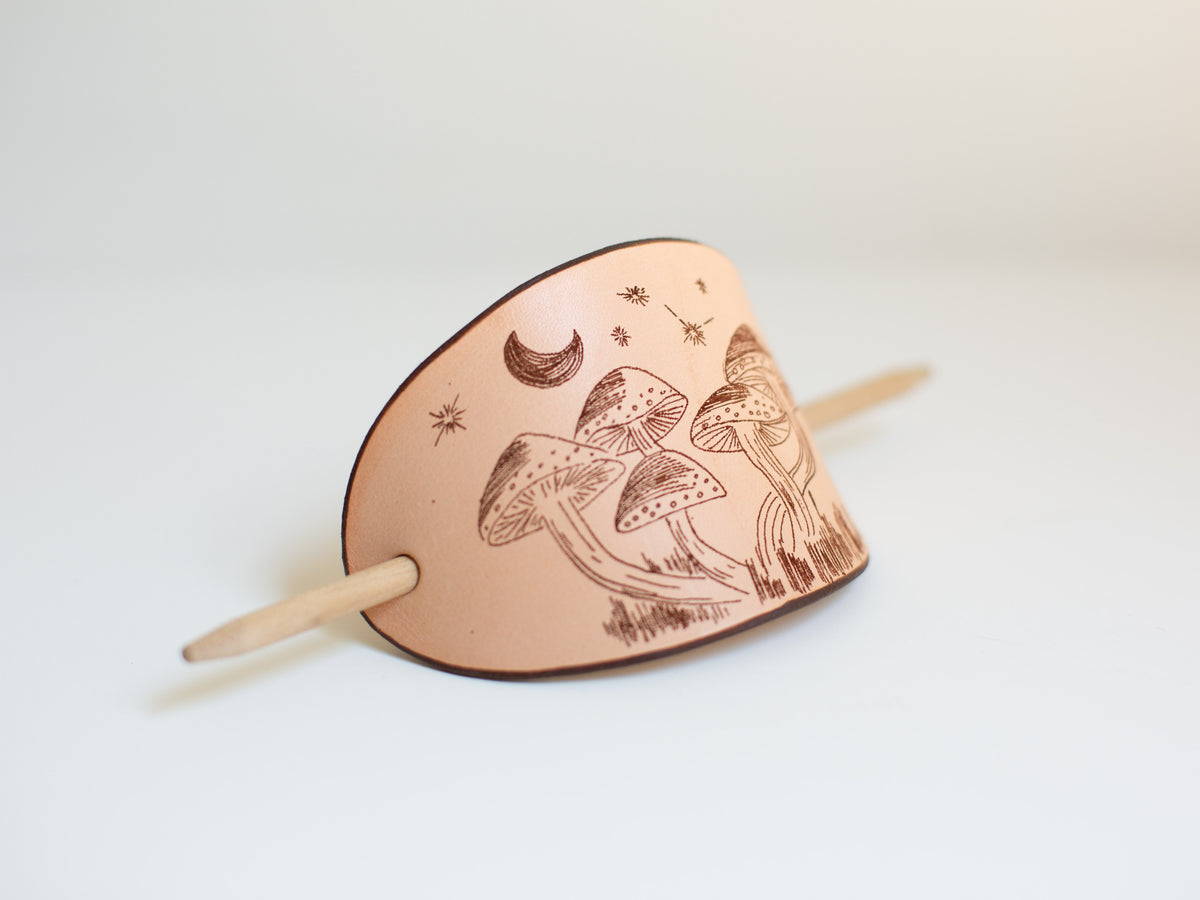 The large barrette is made with non-toxic, sustainably sourced leather and has a laser engraved mushroom design that is the digitalization of an original art drawing. 
