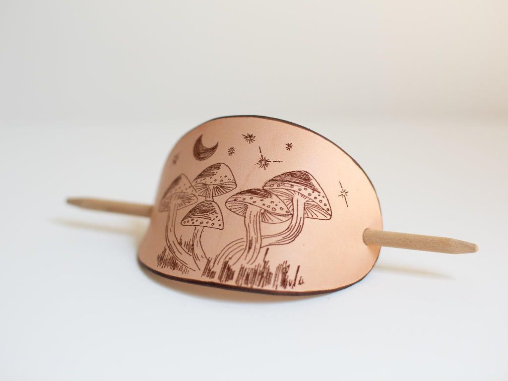 The design on the large organic leather hair stick barrette is the artistic rendering of mushrooms under the night sky. 