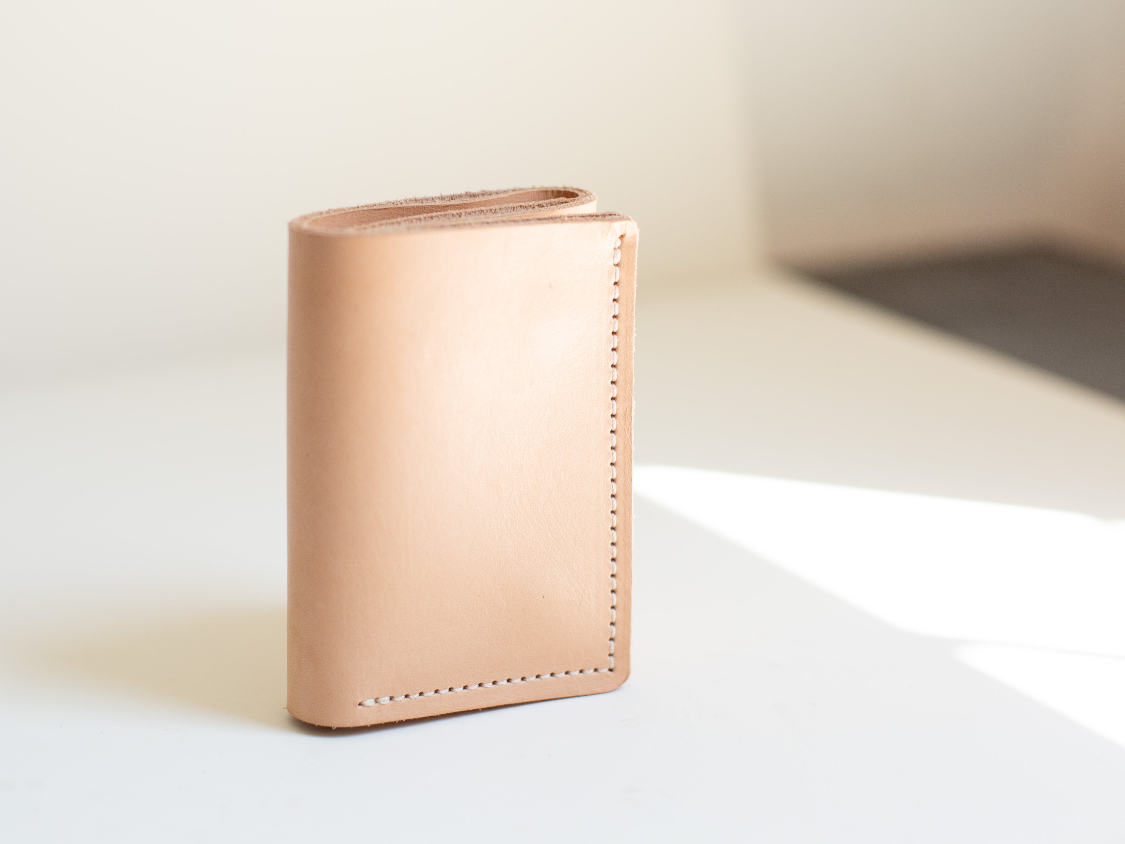 The card wallet made with sustainable leather is seen closed and slightly from the side to show the minimalist design. 