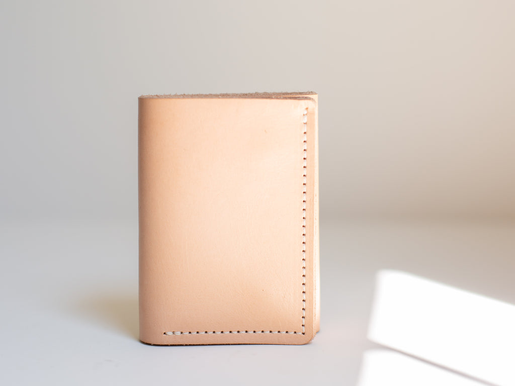 The undyed veg tan leather wallet is closed and shown from the full front. 