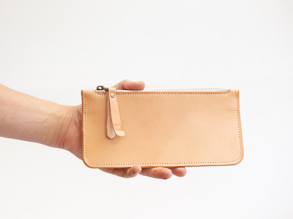 The size of the leather pencil case with zipper is shown in relation to a hand, which is holding the artists case. 