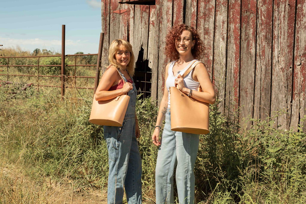 The small and large version of the non-toxic Leather totes, made from ethically sourced leather, are carried by two models to show how they compare in size, and how they look when in use. 