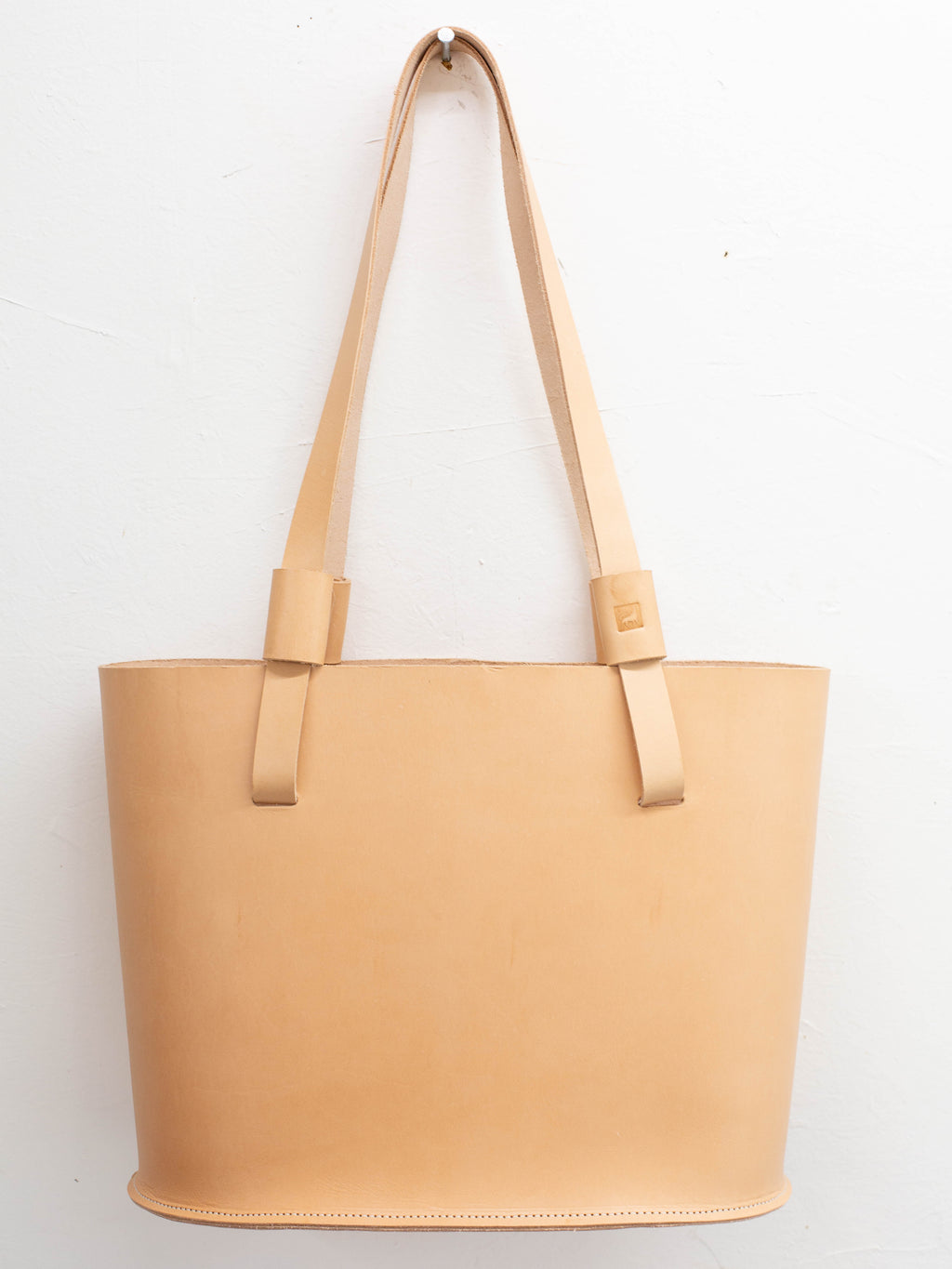 A leather tote bag, that is made from ethically sourced leather, in its natural undyed light tan color. 